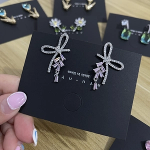 Elegant silver bow earrings with pink crystal pendants on a jewelry display card