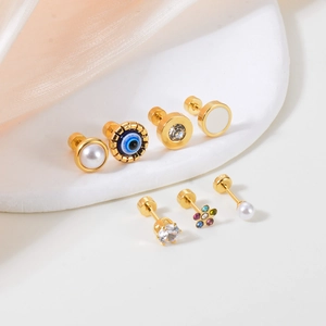 Golden stud earring set with pearls, evil eye, and colorful zircons on white pedestal
