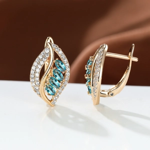 Macro shot of gold leaf earrings featuring four blue marquise stones and micro-set zircons