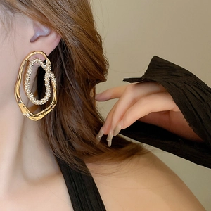 Macro detail of gold plated irregular oval earring with white zircon inlay on model