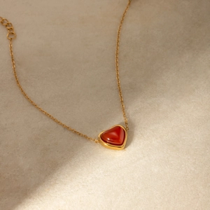 Dettaglio del ciondolo a cuore in agata rossa su catena in acciaio placcato oro 18K