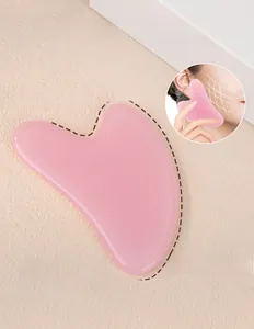 Macro view of heart-shaped pink jade facial gua sha tool for jawline lifting and massage