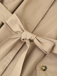 Detailed close-up of khaki trench coat waist belt and high-quality tortoise shell button