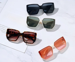 Overhead view of oversized square sunglasses in black, cream, tortoise, and white frames