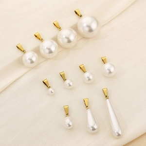 Detail showing white round and teardrop pearl pendants with golden clasps on textured fabric