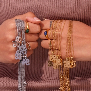 Detail showing hand-held 18K gold plated stainless steel year pendant necklaces