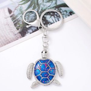Detailed view of silver turtle keychain with blue glitter inlay and metal spring clip