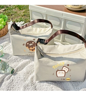 Detail view of insulated canvas lunch bag with cartoon toast print in outdoor picnic setting