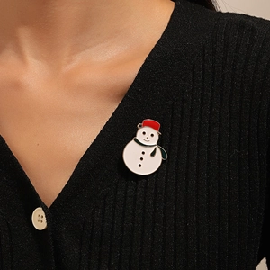 Detailed view of an enamel snowman brooch pinned on a black V-neck cardigan sweater