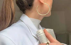 Vue détaillée de grandes créoles dorées polies sur un mannequin en haut blanc