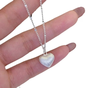Handheld view of S925 sterling silver heart pendant with brushed metallic texture