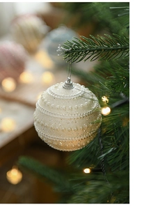 Detail of white pearl textured Christmas ball ornament with glitter on festive tree branch