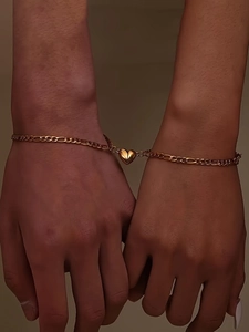 Close-up of gold stainless steel Cuban chain bracelets with magnetic heart charm for couples
