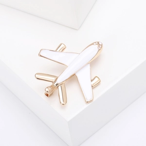 Detailed shot of a gold and white airplane enamel brooch with rhinestones on a white stand