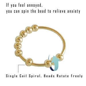 Detail of single coil spiral ring with rotating beads for anxiety relief in gold finish