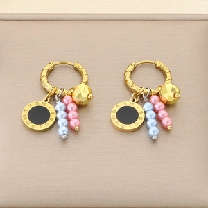 Detail of gold earrings featuring Roman numeral charms and colorful pearl tassel drops
