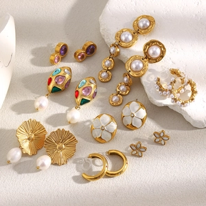 Flat lay of diverse 18K gold plated earrings with pearls, enamel, and colorful gemstones