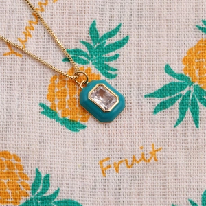 Détail macro d'un pendentif géométrique plaqué or 14k avec émail turquoise et cristal