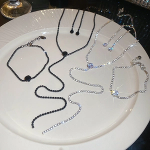 Detail of crystal pendant necklaces and bracelets in black and silver on white plate