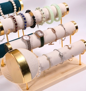 Detail of 4-tier jewelry stand featuring gold metal end caps and soft cream fabric texture