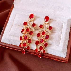 Macro detail of vintage gold fringe earrings with red zircon stones on velvet