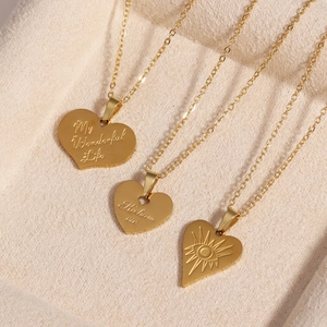 Detailed macro view of three gold heart pendants with unique engraved patterns and text