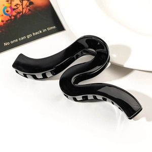 Close-up of a glossy black S-shaped hair claw clip with elegant minimalist curves