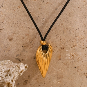 Gold feather pendant necklace with black wax cord on natural stone background