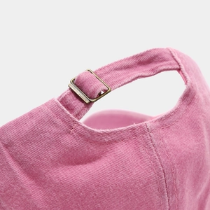 Close-up of vintage bronze buckle and pink washed cotton texture on baseball cap
