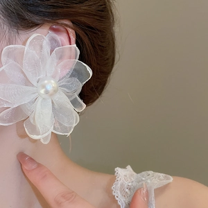 Close-up of asymmetrical chiffon flower earrings with a white pearl on a fashion model