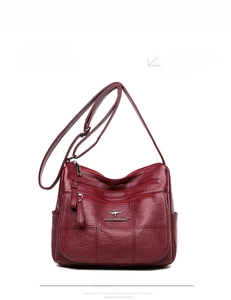 Detail of red textured leather shoulder bag with double zip pockets and kangaroo logo