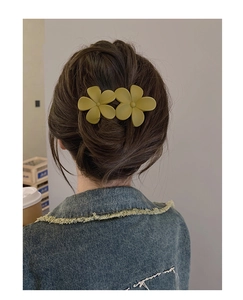 Close-up of olive green matte flower hair claw clip on model's elegant updo hairstyle