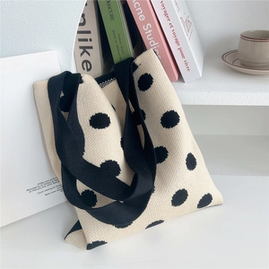 Elegante borsa tote in maglia beige a pois neri esposta in un ambiente minimalista