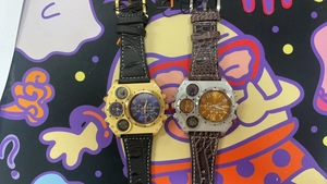 Detail view of large multi-timezone watches with gold and silver cases on leather straps