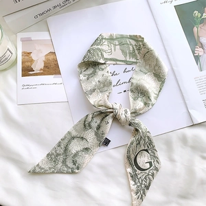 Detail of silk-feel scarf with letter G and forest green floral print on white ribbon
