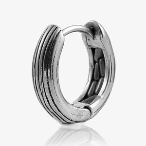 Macro shot of vintage silver steel hoop earring with vertical lines and chain texture