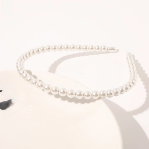 Detailed view of white pearls headband on a white porcelain dish with elegant lighting