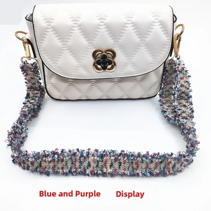 Detail of white quilted bag featuring a colorful woven strap and gold flower clasp