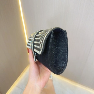 Detail of elegant black evening clutch bag with glitter texture and rhinestone stripes