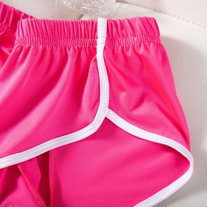 Detailaufnahme des elastischen Bundes und der weißen Paspelierung an pinken Shorts