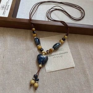 Détail du collier ethnique avec pendentif coeur bleu sur fond de toile de lin
