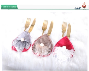 Close-up of festive gnome cutlery holders for Christmas table settings with gold utensils