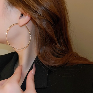 Close-up of model wearing large golden geometric hoop earrings with a metallic finish