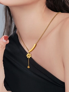 Detailed view of daisy pendant necklace in gold finish on model neck and black clothing