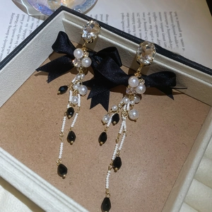 Detailed shot of bowknot earrings with long tassels and pearls on a jewelry box