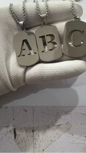 Détail de trois pendentifs lettres évidées A, B et C en argent sur des chaînes à billes