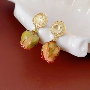 Handmade real rose bud earrings with gold hammered discs on a white shell plate