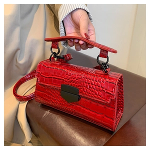 Detail of red crocodile texture PU leather handbag with black metallic lock and handle