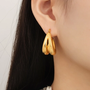 Golden double-layered teardrop earrings with grooved texture and mirror finish on model