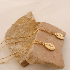 Macro detail of golden oval pendant with rose engraving on natural stone background